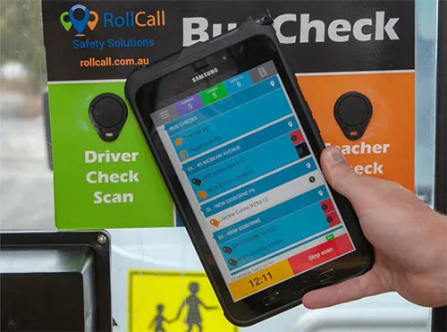 A student tapping an NFC card on a RollCall scanner as they board the school bus