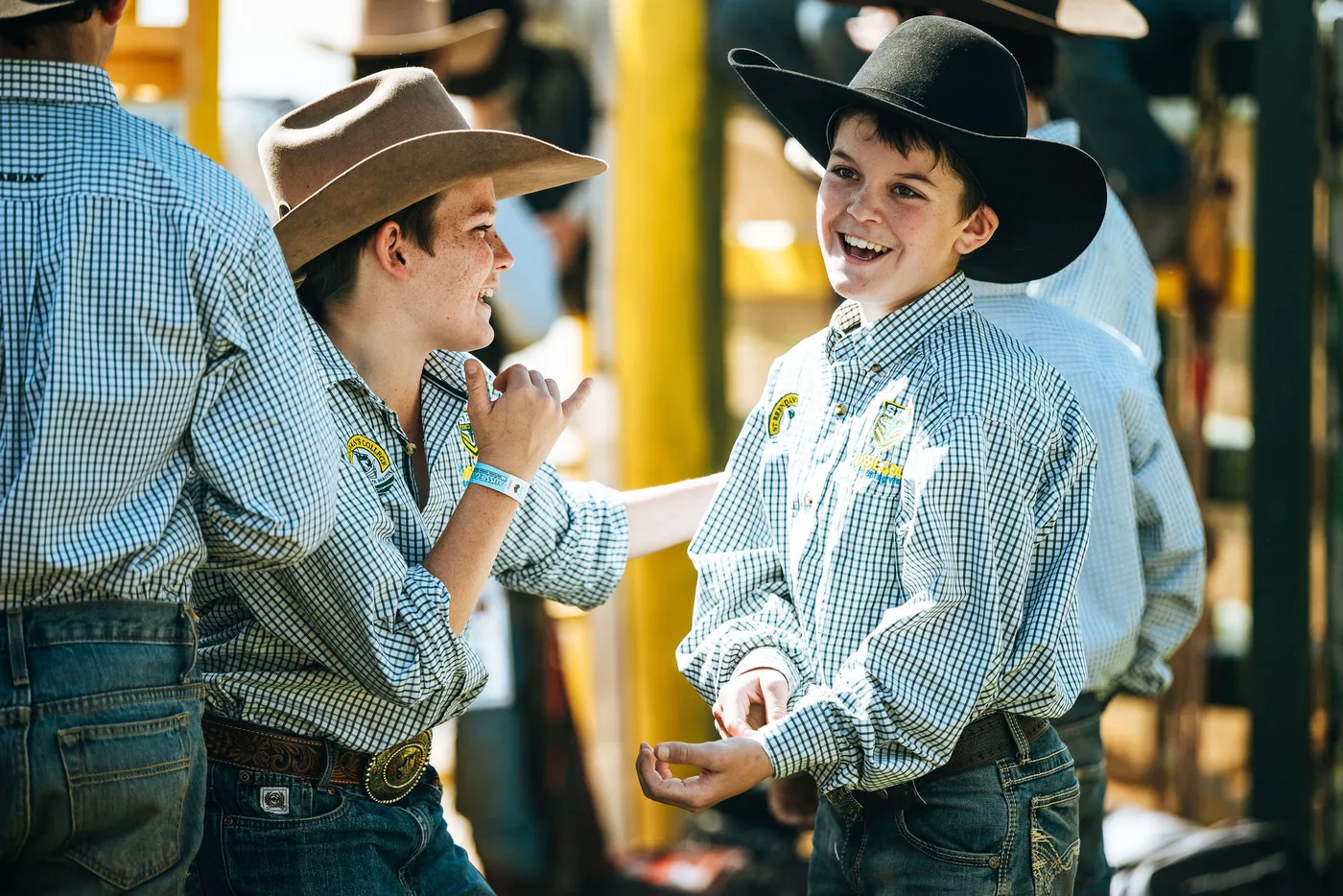Two St Brendan's students in school shirts and hats, laughing together behind the chutes before their rides.